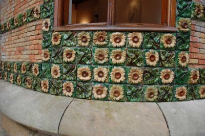 DSC_1220 Sonnenblumen.JPG (141.11 KiB) 9215 mal betrachtet Auffällig ist die Gestaltung des Gebäudes mit einer Vielzahl von Sonnenblumenmustern, die in horizontalen Streifen entlang der gesamten Fassade und dem zylindrischen Turm, der sich über dem Portikus des Eingangs erhebt, angeordnet sind.