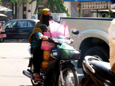 Obwohl in Siem Reap noch nicht allzu viele Mopeds <br />fahren, schützen die Zweiradfahrer ihre Atemwege